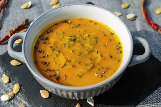 A bowl of pumpkin soup with seeds on top